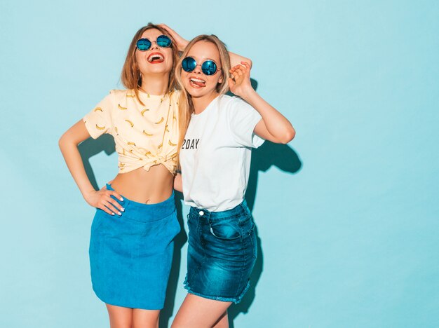Deux jeunes belles filles hipster blondes souriantes en jeans d'été à la mode jupent les vêtements.