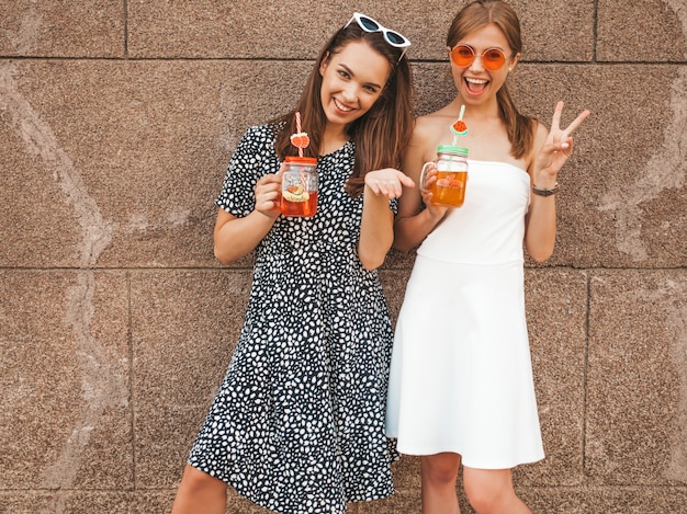 Deux jeunes belles filles hipster souriantes en robes d'été à la mode.