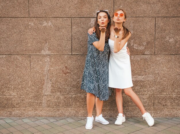 Deux jeunes belles filles hipster souriantes en robes d'été à la mode.