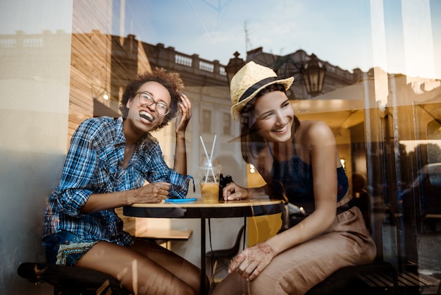 Deux jeunes belles filles souriant, riant, se reposant au café. Tiré de l'extérieur.