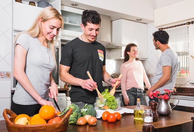 Deux jeunes couples préparant ensemble des plats dans la cuisine