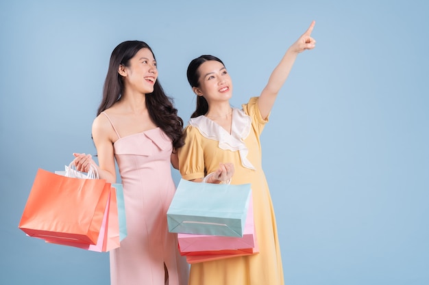 Deux Jeunes Femmes Asiatiques Tenant Un Panier Sur Fond Bleu Photo Premium