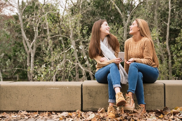 Photo gratuite deux jeunes femmes assises et parlant dans le parc