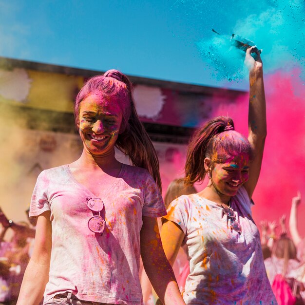 Deux jeunes femmes couvertes de couleurs holi dansant dans le festival de holi