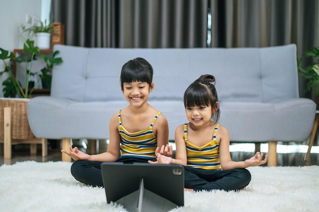 Photo gratuite deux jeunes femmes faisant du yoga dans une chambre sur un tapis blanc. mise au point sélective.