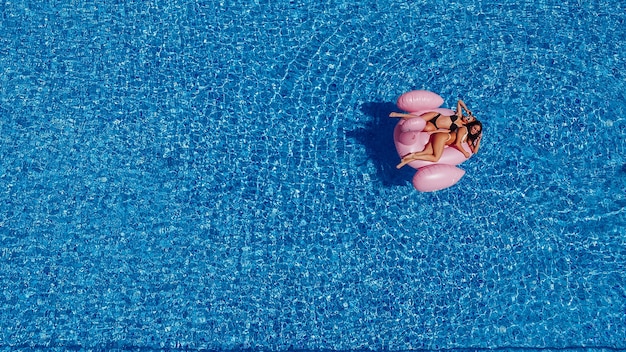 Deux jeunes femmes heureuses avec des chiffres nagent dans la piscine pour les flamants roses. Vue de dessus.