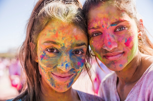 Deux jeunes femmes ont couvert son visage avec de la poudre de couleur holi