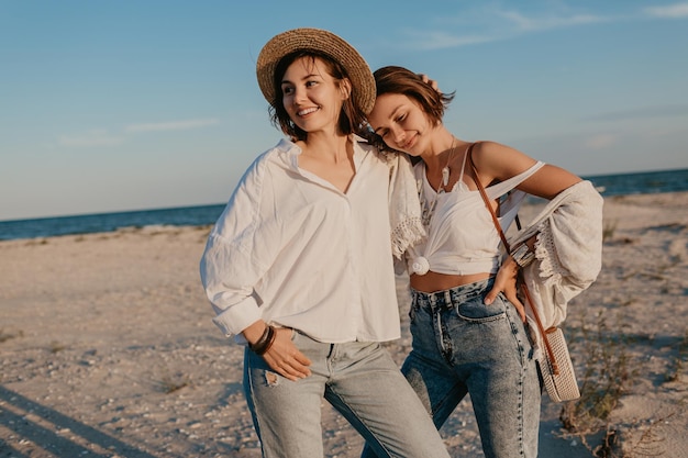 Photo gratuite deux jeunes femmes s'amusant sur la plage au coucher du soleil