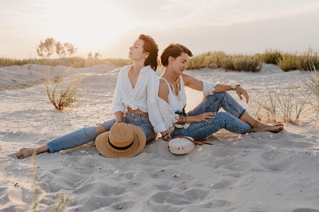 Deux jeunes femmes s'amusant sur la plage au coucher du soleil
