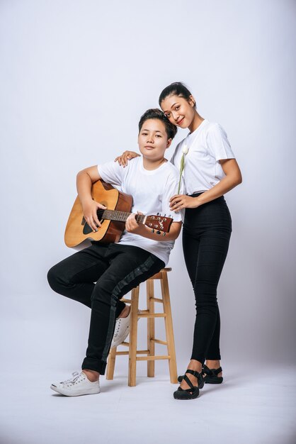 Deux jeunes femmes se sont assises sur une chaise et jouaient de la guitare.