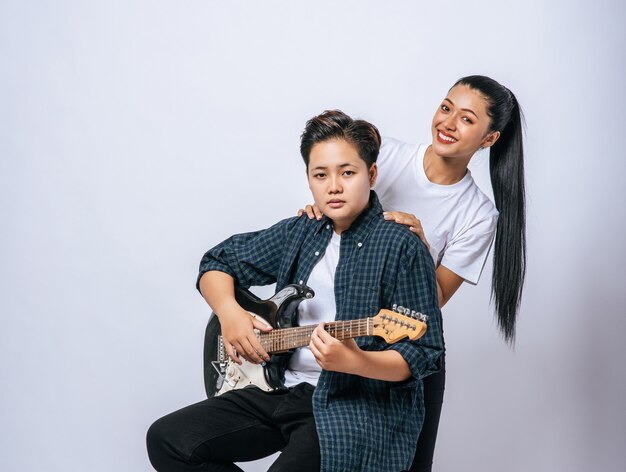 Deux jeunes femmes se sont assises sur une chaise et jouaient de la guitare.