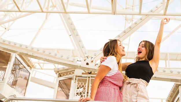 Deux jeunes femmes se tenant devant la grande roue se moquer