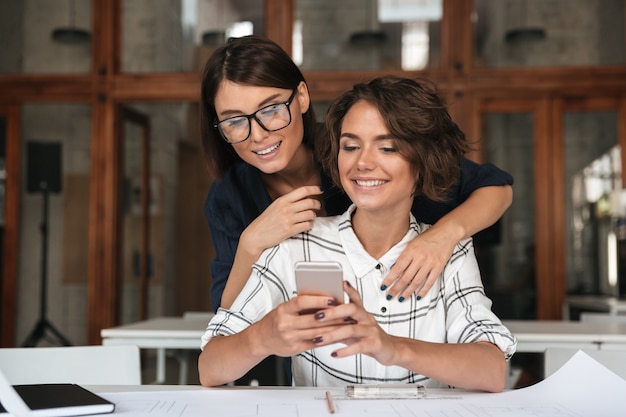 Deux, jeunes femmes, utilisation, smartphone, table