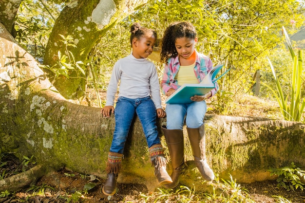 Deux jeunes filles sur l&#39;arbre en train de lire ensemble