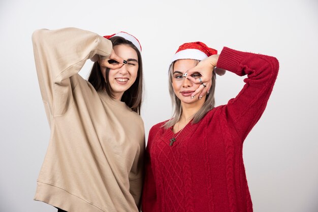 Deux jeunes filles en bonnet de Noel debout et posant.