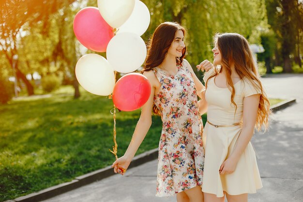 deux jeunes filles brillantes passent leur temps dans le parc d&#39;été avec des ballons