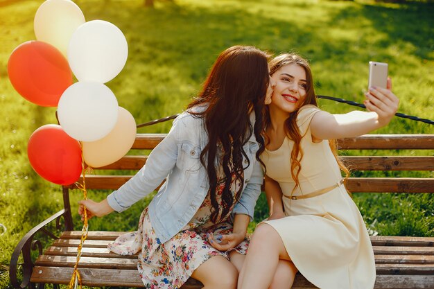 deux jeunes filles brillantes passent leur temps dans le parc d&#39;été avec des ballons