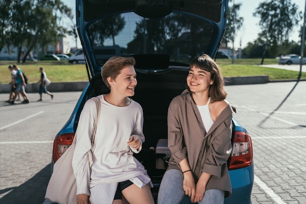 Deux jeunes filles dans le parking au tronc ouvert posant