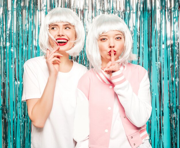 Deux jeunes filles sexy hipster en perruques blanches et lèvres rouges. Belles femmes à la mode dans les vêtements d'été.