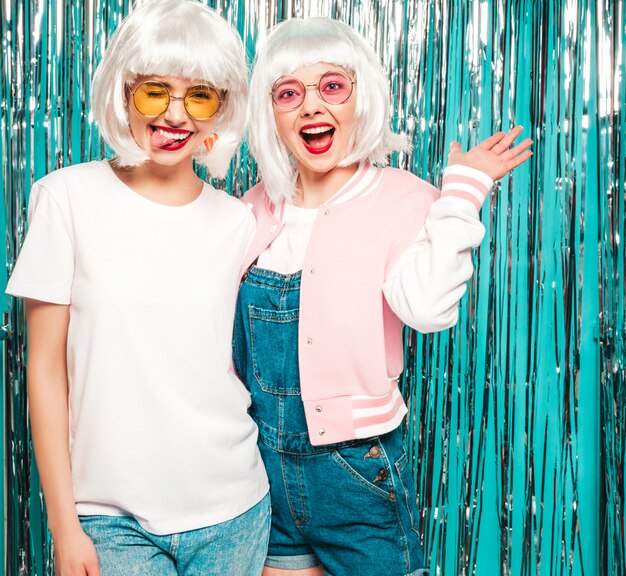 Deux jeunes filles sexy hipster en perruques blanches et lèvres rouges.Belles femmes à la mode en vêtements d'été d'été en lunettes de soleil