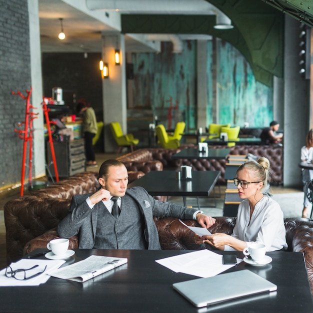 Photo gratuite deux jeunes hommes d'affaires analysant un document dans un restaurant