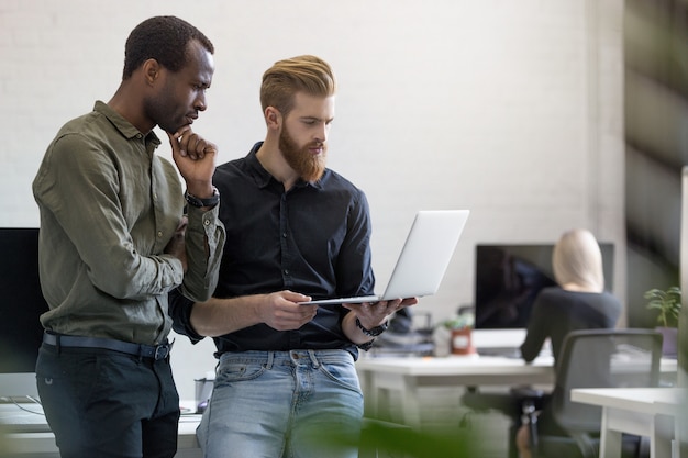 Photo gratuite deux jeunes hommes d'affaires inquiets en regardant l'ordinateur portable