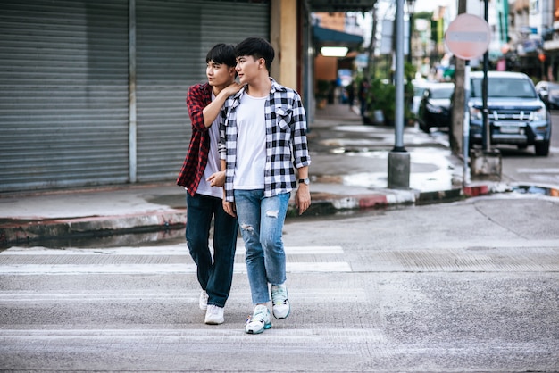 Deux jeunes hommes aimants en chemises et marchant dans la rue.