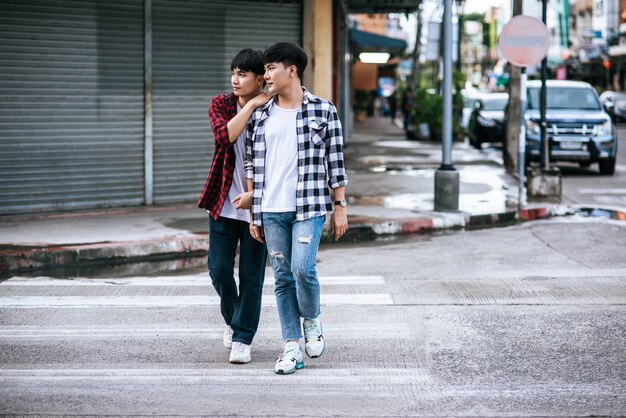 Deux jeunes hommes aimants en chemises et marchant dans la rue.