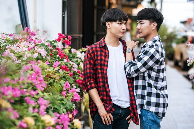 Deux jeunes hommes bien-aimés en chemises et debout sur le trottoir.