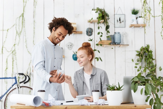 Deux jeunes ingénieurs ou architectes utilisant des gadgets électroniques pendant une petite pause au bureau