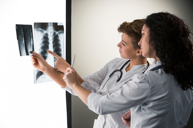 Photo gratuite deux jeunes médecins attrayants à la recherche de résultats de radiographie