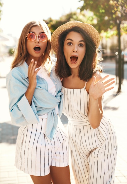 Photo gratuite deux jeunes modèles brune et blonde posant dans la rue