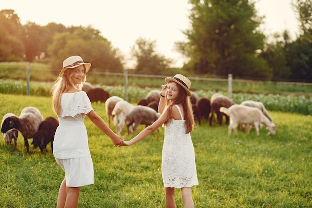 Photo gratuite deux jolies filles dans un champ avec une chèvre