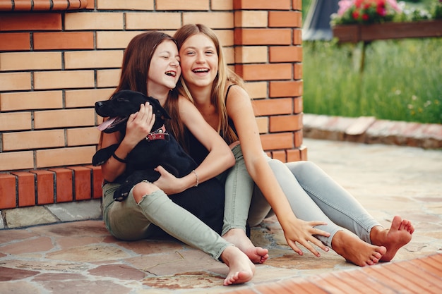 Photo gratuite deux jolies filles dans un parc d'été avec un chien