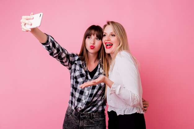 Deux jolies filles faisant autoportrait par téléphone mobile