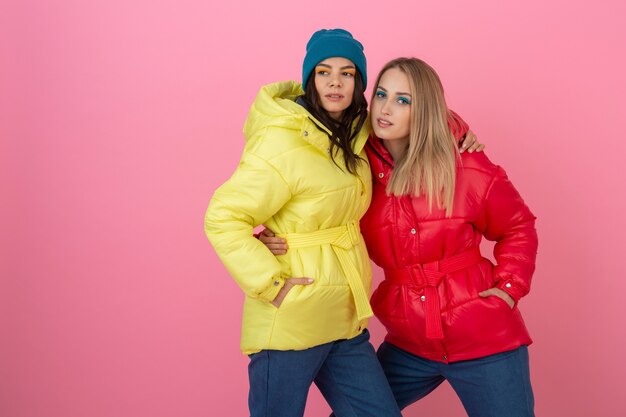 Deux jolies filles posant sur fond rose en veste d'hiver colorée de couleur rouge et jaune vif