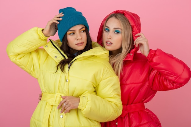 Deux jolies filles posant sur fond rose en veste d'hiver colorée de couleur rouge et jaune vif