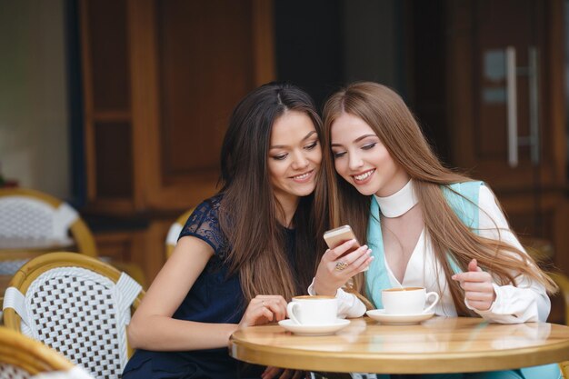 deux jolies jeunes femmes au café avec café et téléphone