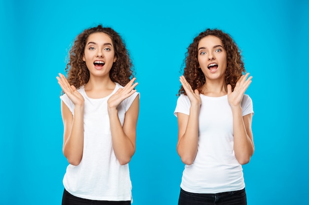 Deux jumeaux filles surpris sur mur bleu