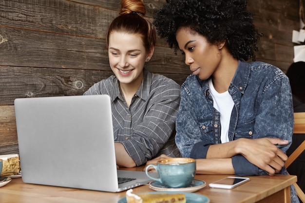 Photo gratuite deux lesbiennes élégantes assis au café devant un ordinateur portable ouvert