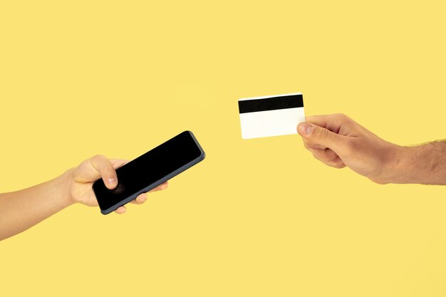 Deux mains mâles tenant un téléphone portable ou un smartphone et une carte de crédit