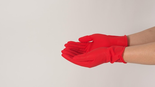 Deux mains portent des gants en latex rouge et mendient sur fond blanc.