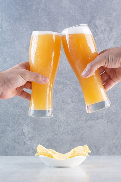 Deux mains tenant deux verres de bière délicieuse.