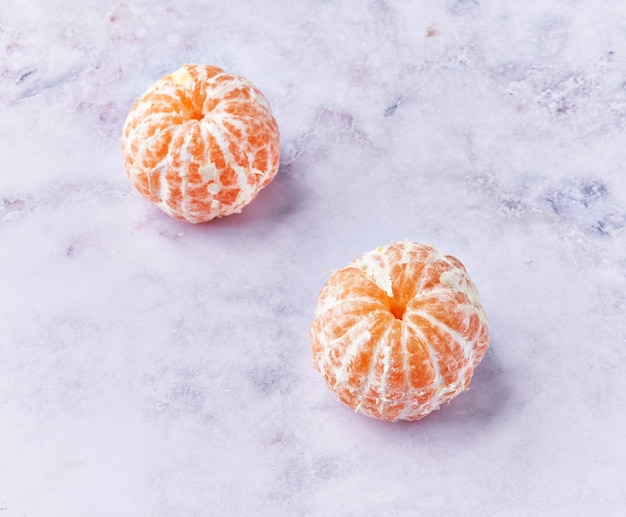 Photo gratuite deux mandarines pelées à la surface du marbre