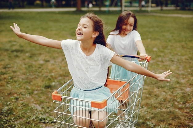 deux mignonnes petites filles en T-shirts blancs et jupes bleues jouent dans la balade en parc d&#39;été