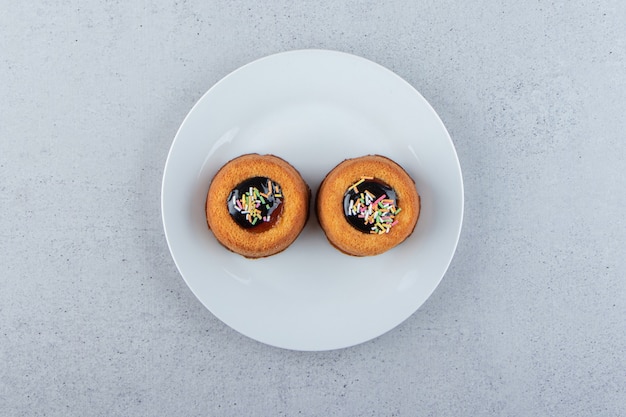 Deux mini gâteaux avec de la gelée placés sur une assiette blanche. photo de haute qualité