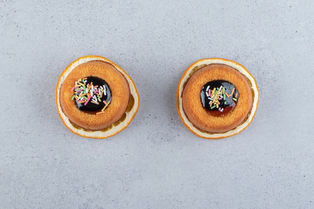 Deux Mini Gâteaux Avec De La Gelée Placés Sur Une Tranche D'orange. Photo De Haute Qualité