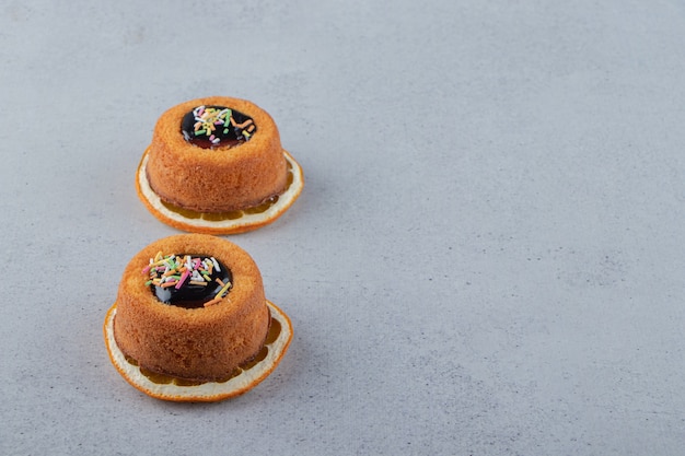 Deux mini gâteaux avec de la gelée placés sur une tranche d'orange