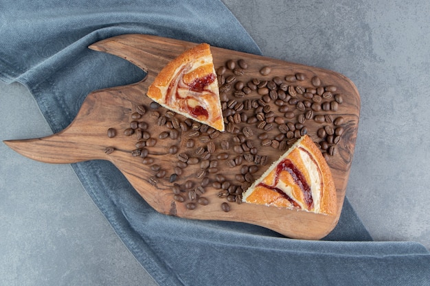 Deux Morceaux De Gâteaux Avec Des Grains De Café Sur Une Planche à Découper En Bois