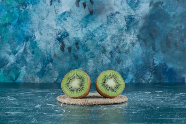 Deux morceaux de kiwi sur dessous de plat, sur la table en marbre.